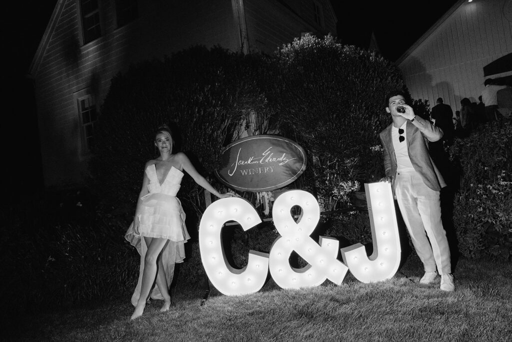 Bride and groom posing by their light up initials after their wedding welcome night. 