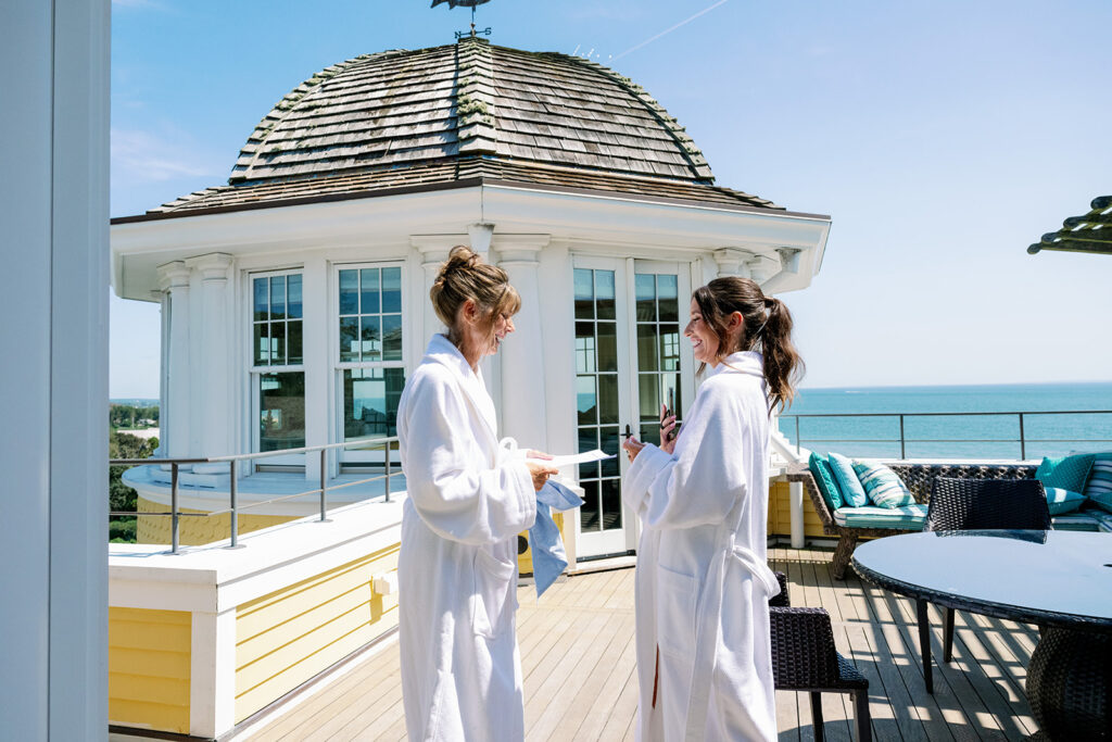 Bride's mom and sister sharing a candid moment on the Ocean House Carousel Suite balcony.