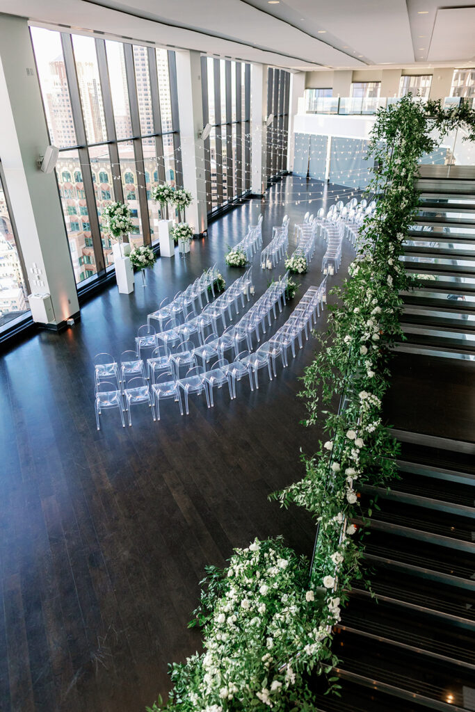 Boston State Room wedding ceremony with classic white florals and ghost chairs. 