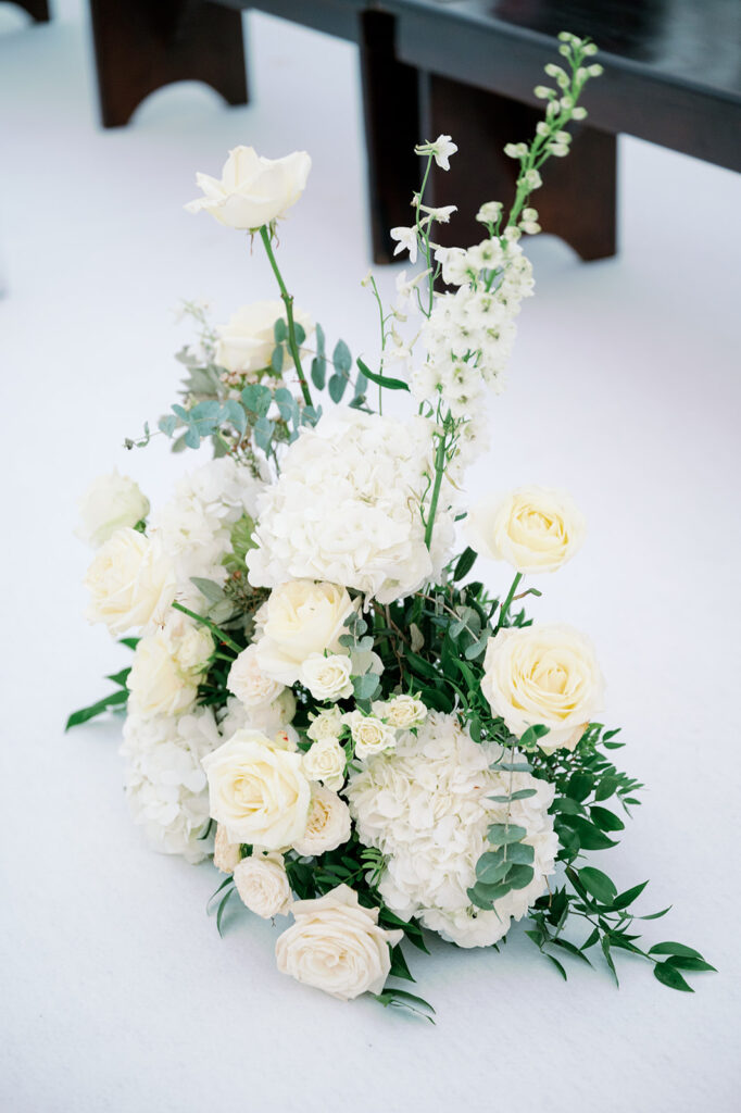 Wedding ceremony aisle white floral arrangements.