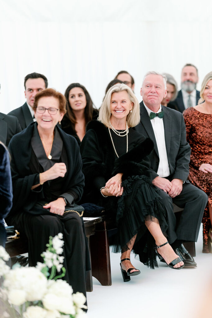 Guests sitting runway-style watching a wedding ceremony and smiling.
