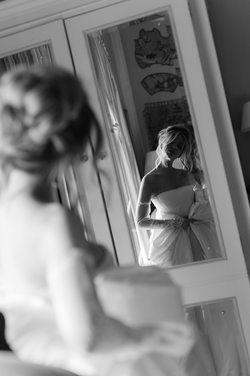 Candid shot of a bride looking at herself in a wardrobe mirror.
