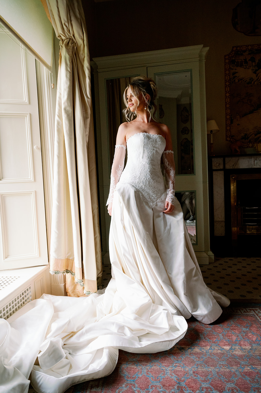 Bride in a stunning Abel Honor NYC wedding gown looking out of a large window. 