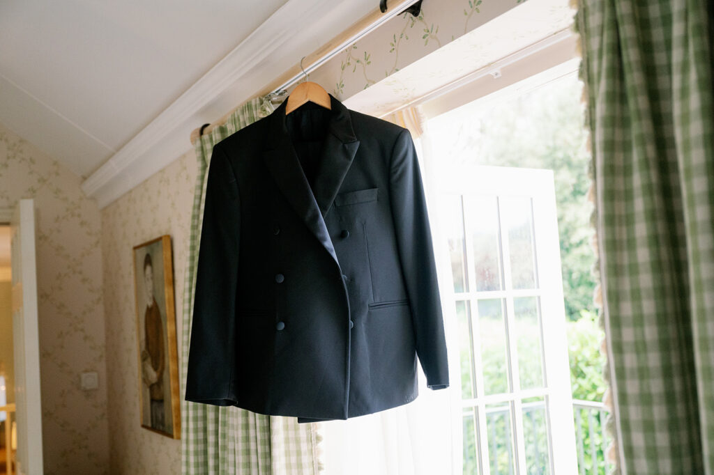 Black groom jacket hanging on a curtain rod at Ballyfin Demesne.