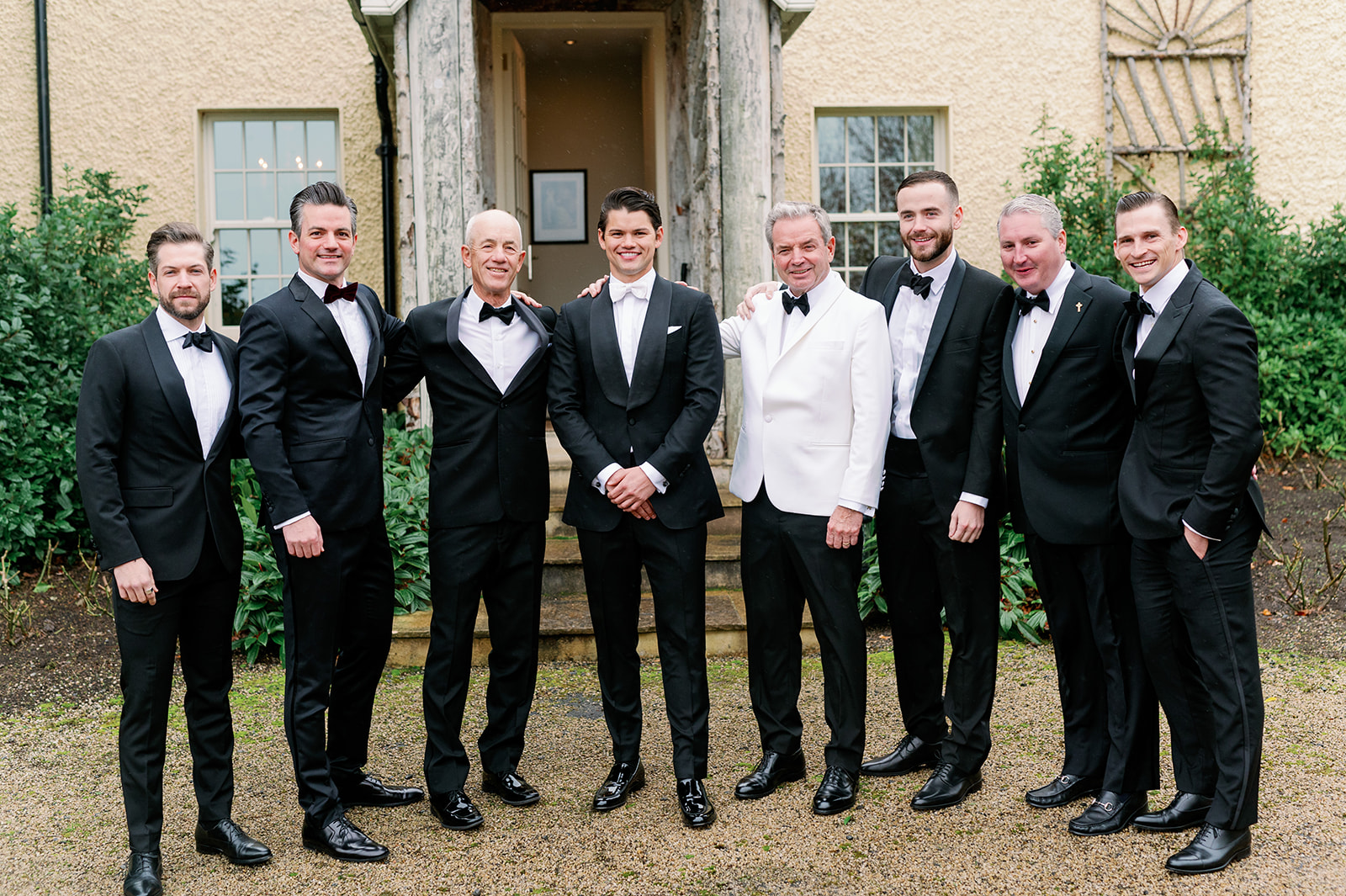 Groom and groomsmen wearing black and white tuxedos standing outside Ballyfin Demesne.