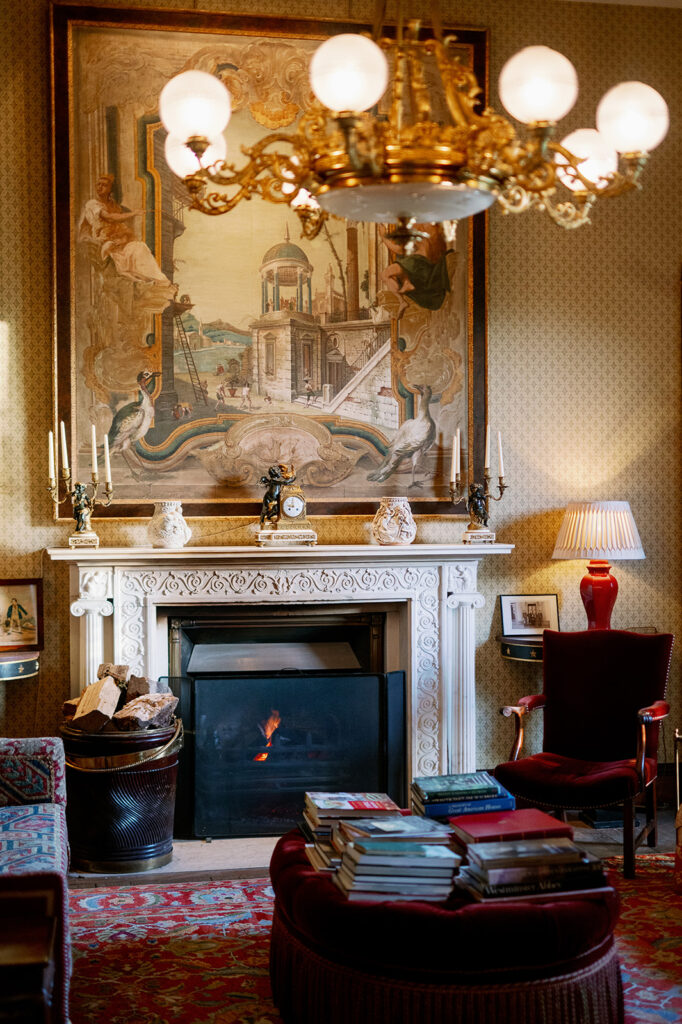 A fireplace inside Ballyfin Demesne in Ireland featuring neoclassical artwork.
