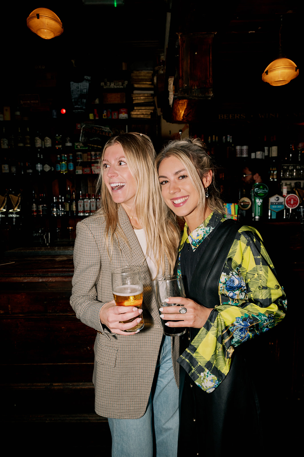 Two women holding glasses of beer at a welcome party at the Temple Bar pub in Dublin, Ireland.