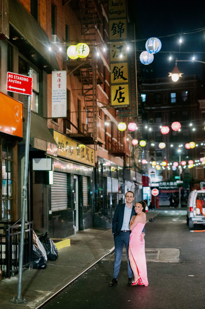 Couple standing in the street of China Town, New York posing for their urban engagement photos. 