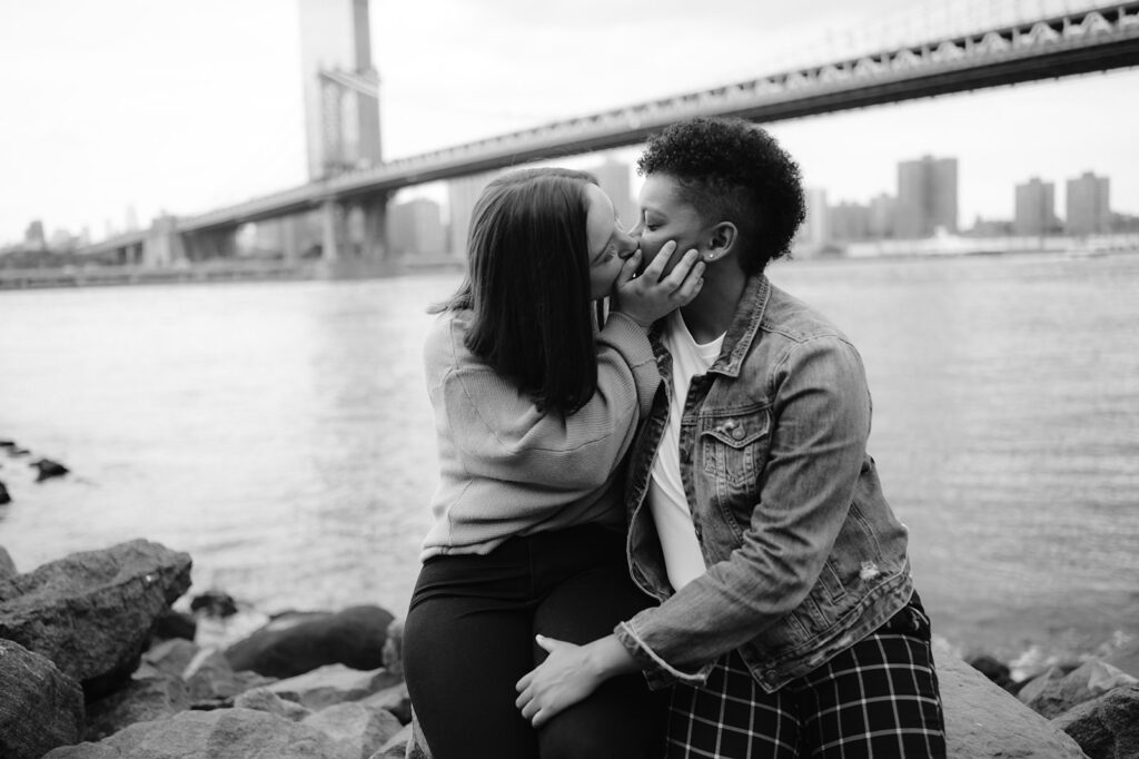 Couple kissing in DUMBO, NYC under the Manhattan Bridge for their engagement photos. 