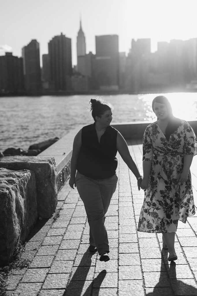 Couple candidly walking in Long Island City with the NYC skyline in the background. 