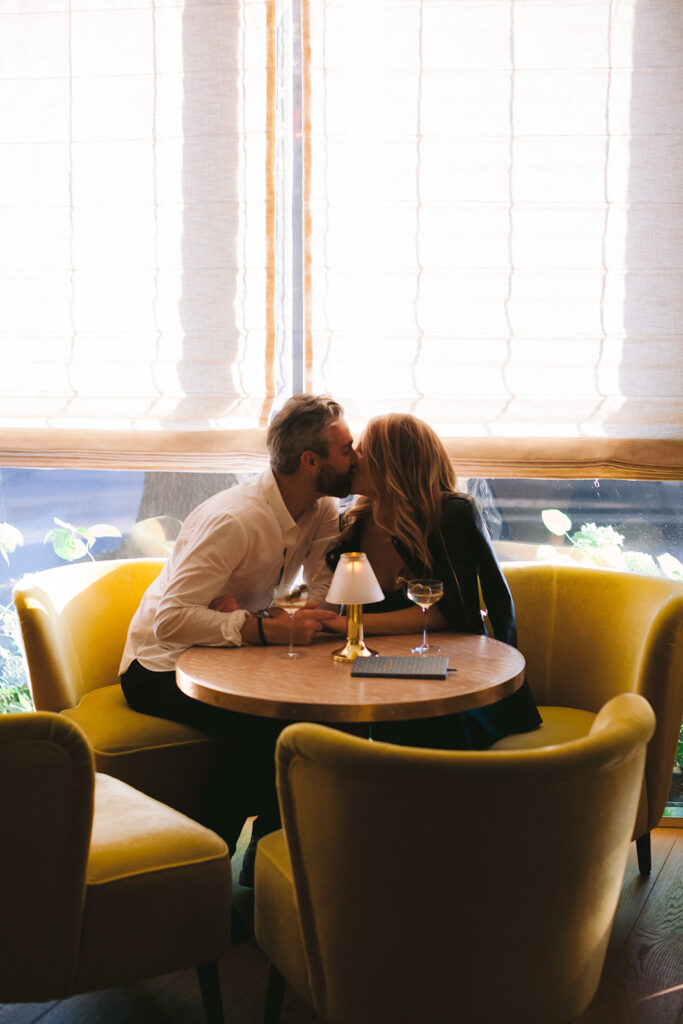 Couple kissing in a New York cocktail bar for their engagement photo session. 
