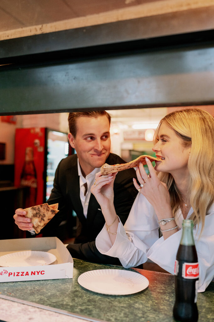 Couple sharing NYC pizza during their engagement photoshoot.