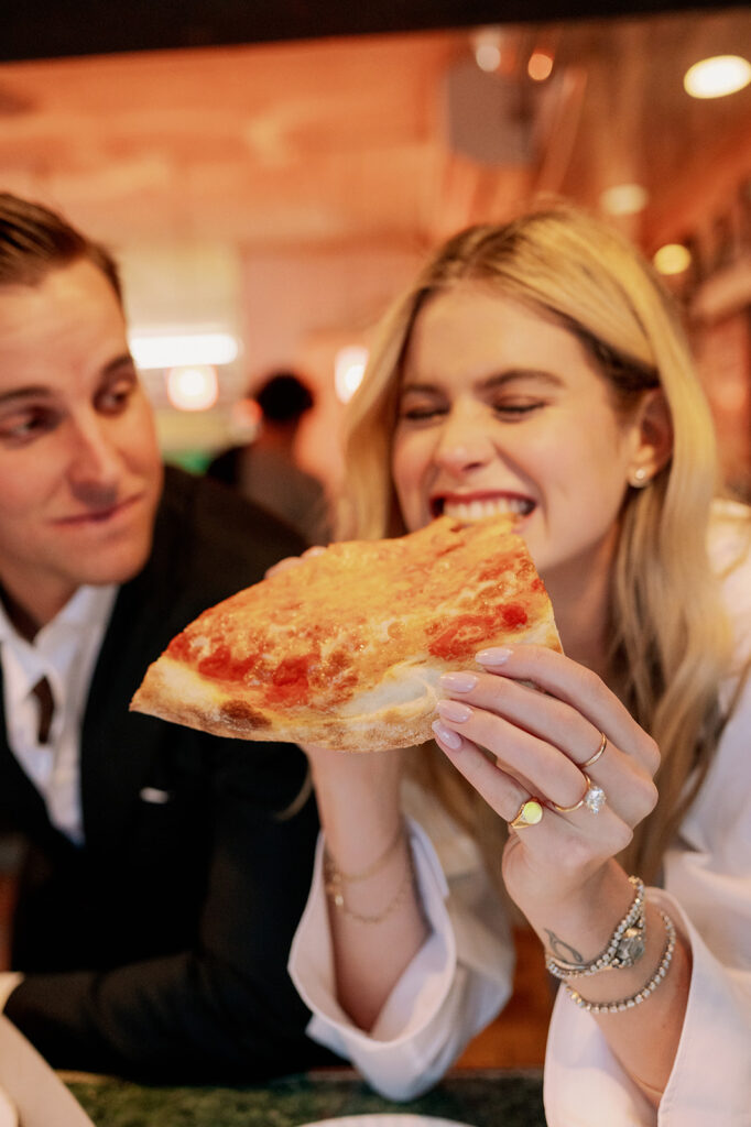 Couple eating a slice of New York style pizza. 