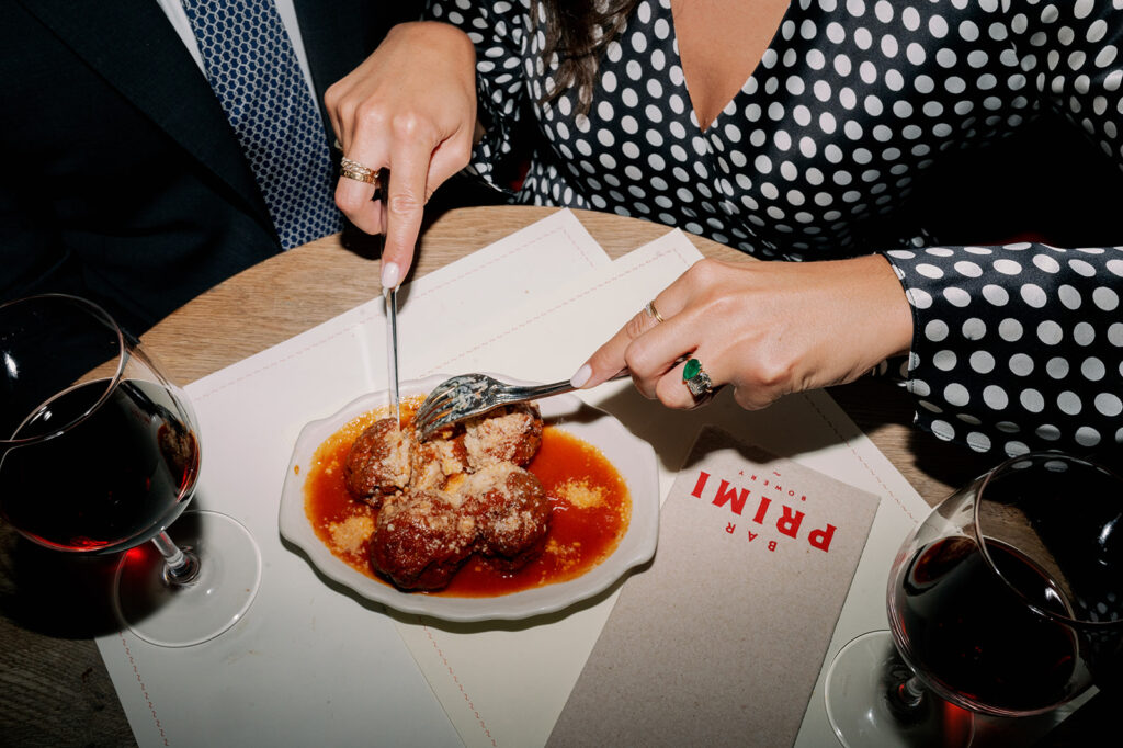 Couple cutting into pasta and meatballs at their favorite NYC restaurant. 