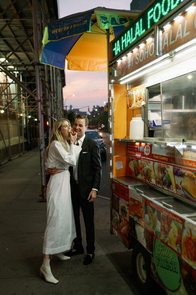 Cute couple sharing a hot dog at a local New York City hot dog stand. 