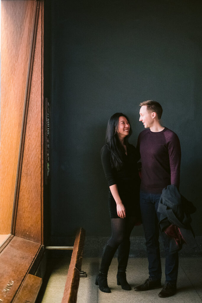 Couple standing next to an exhibit in a New York City museum for their engagement photo session.