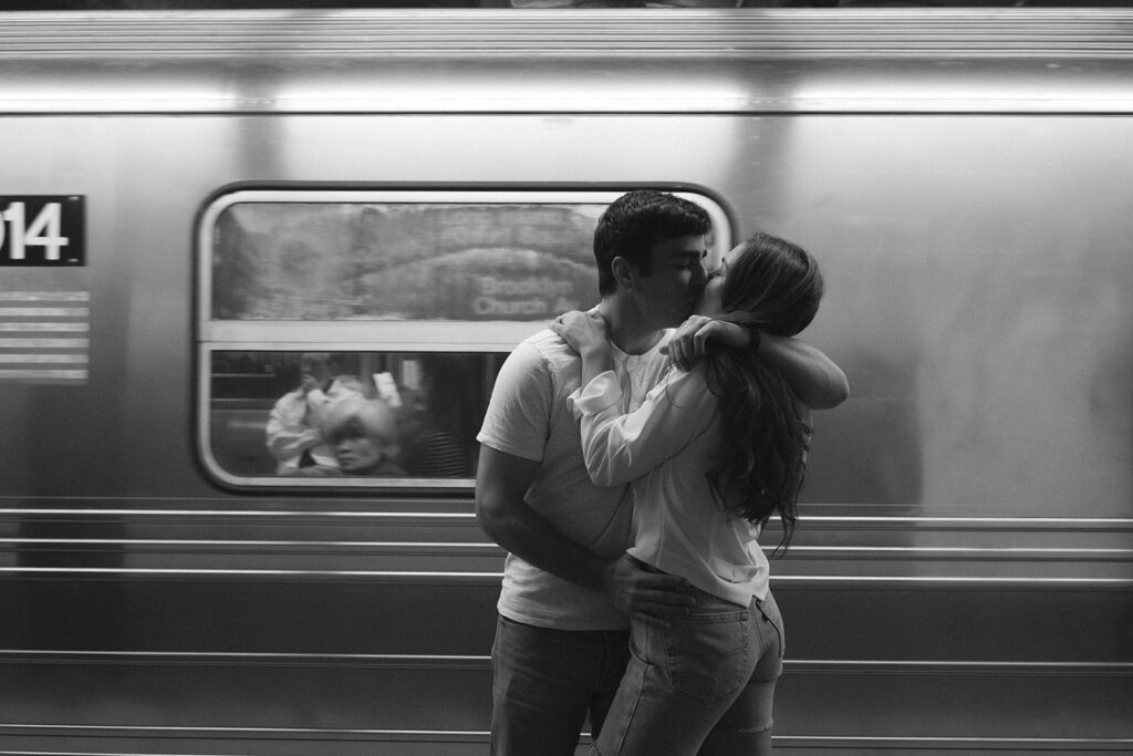Cute couple sharing a candid kiss outside a New York City subway train. 