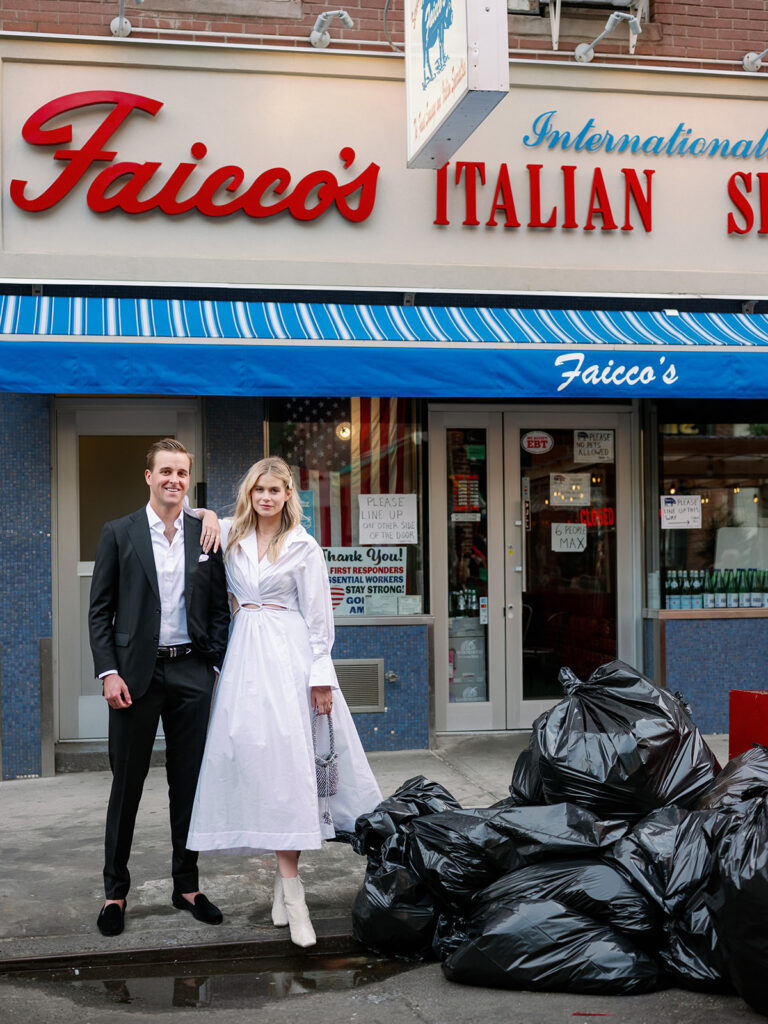 Two stunning models standing next to a pile of trash posing for their engagement photoshoot. 