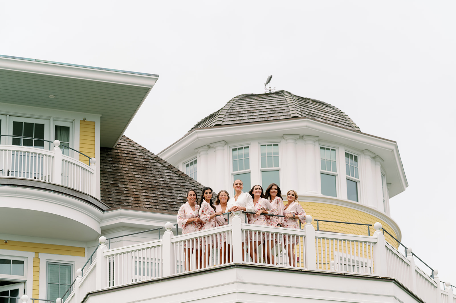 Getting ready portraits of the bride and bridesmaids standing on a large white balcony outside Ocean House in Rhode Island.