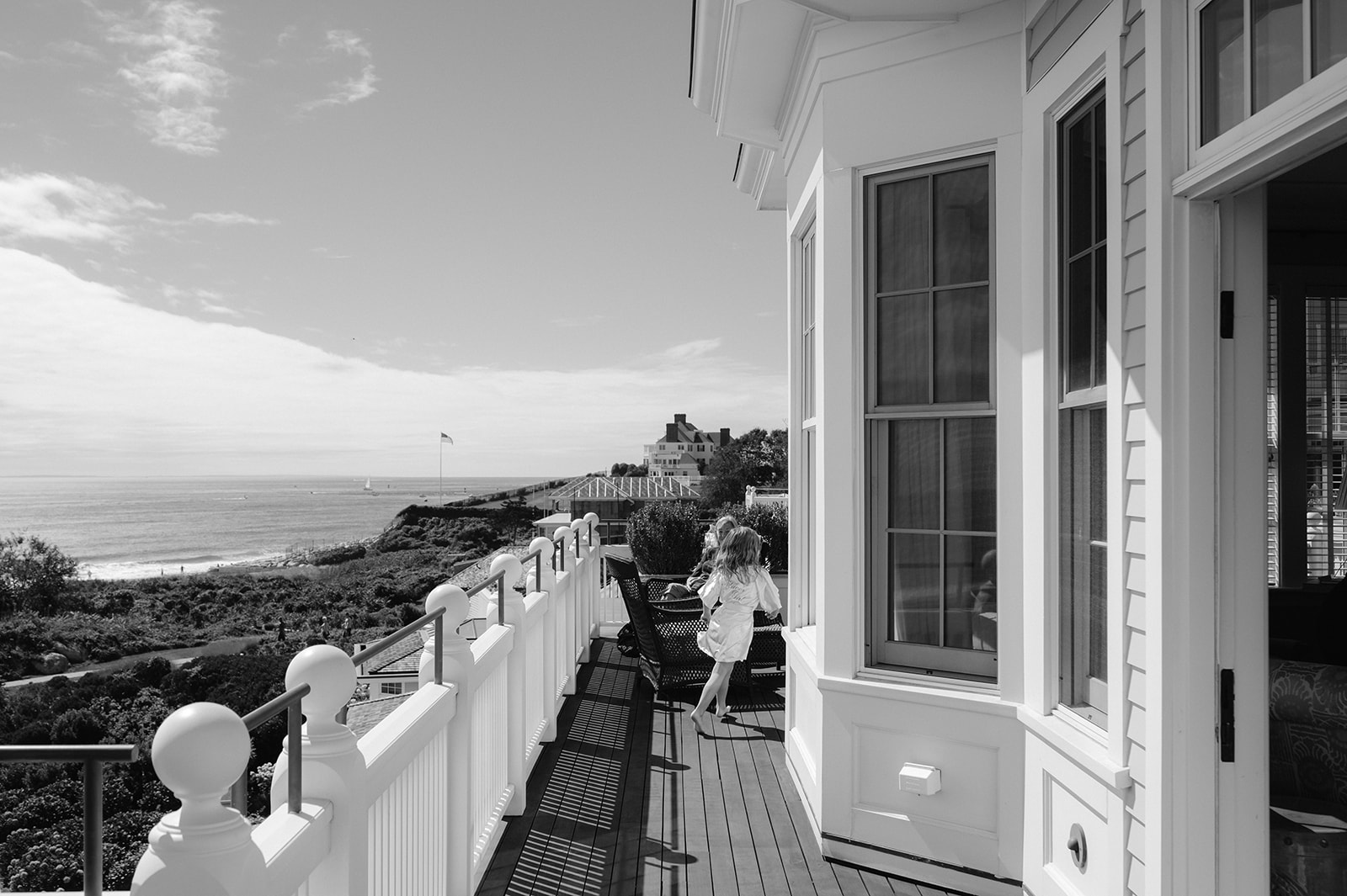 Black and white candid shot of a little girl running on a beachfront balcony at Ocean House in Rhode Island.
