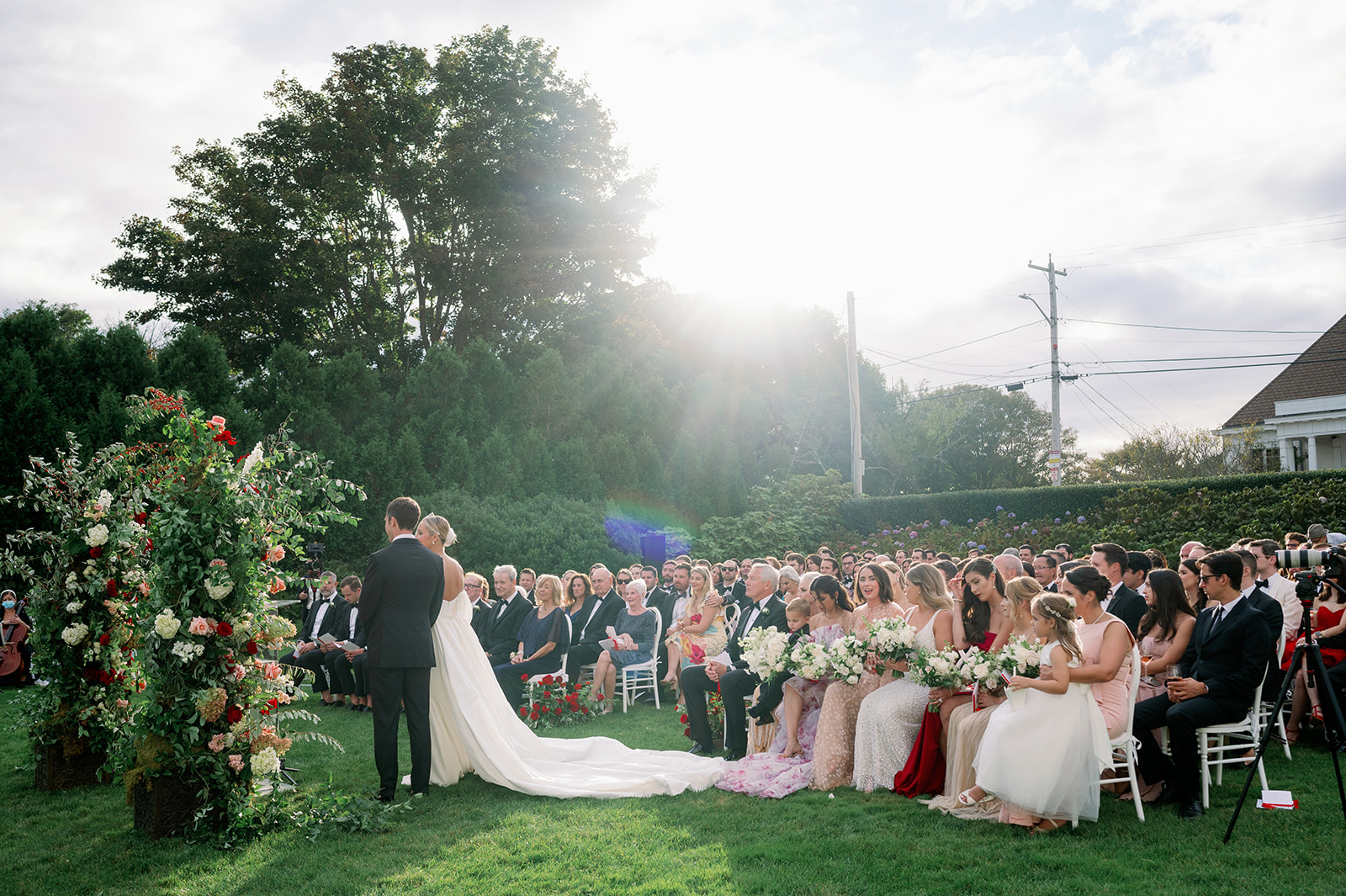 Outdoor wedding ceremony on the lawn of Ocean House in Rhode Island with a floral arch. 