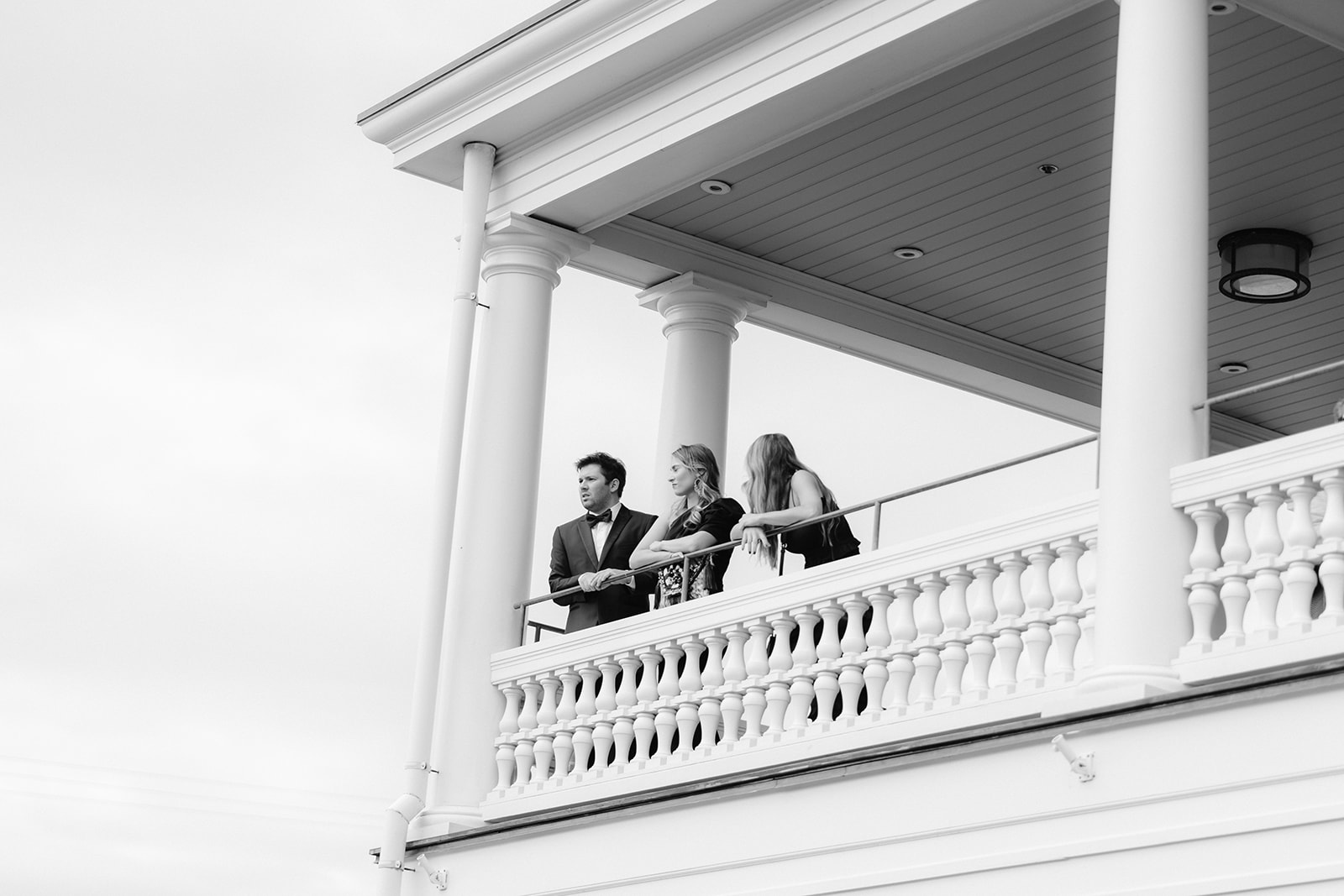 Candid black and white capture of wedding guests on the balcony of Ocean House awaiting the ceremony.