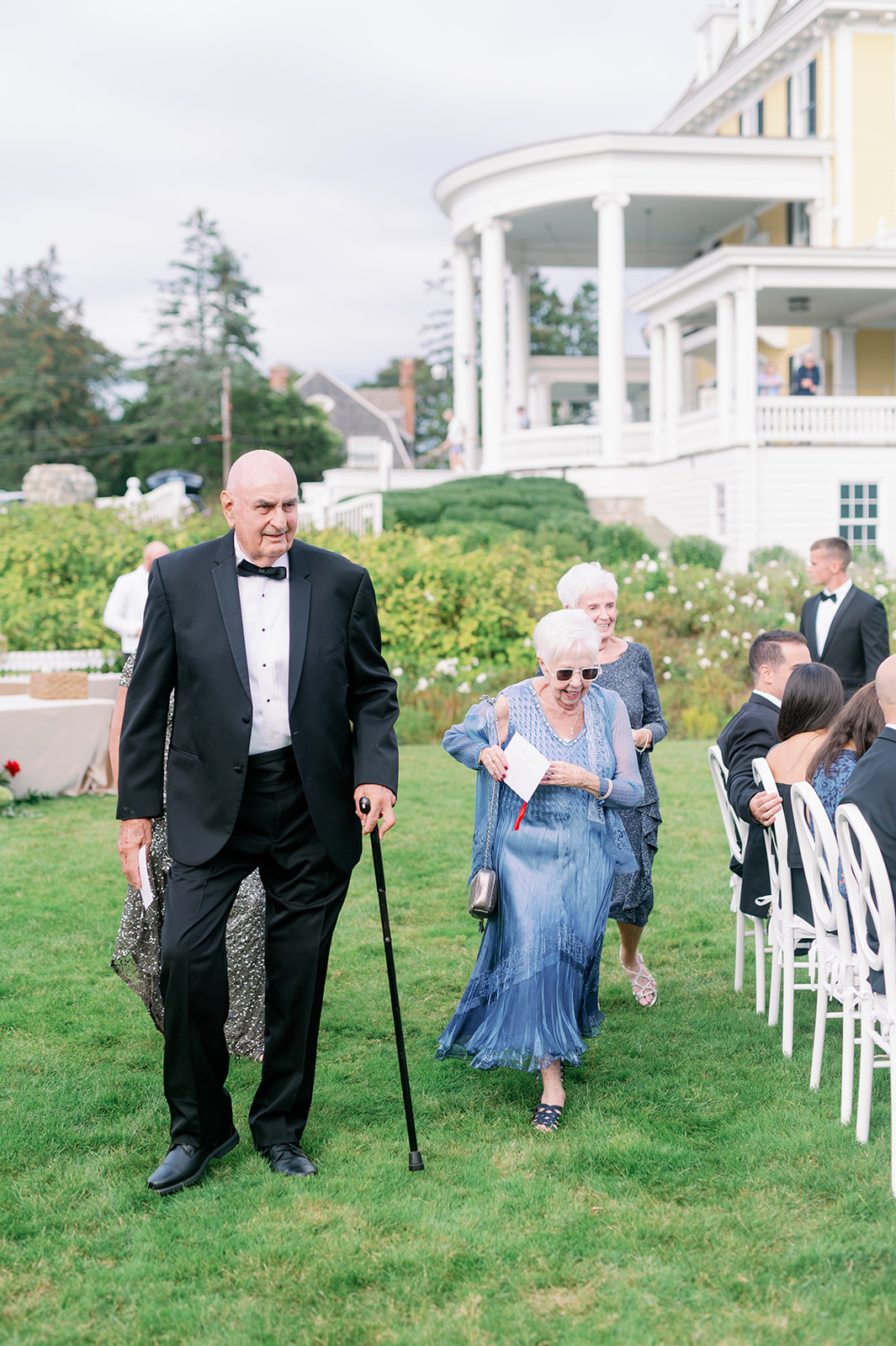 Elderly wedding guests walking to their ceremony seats on the lawn of Ocean House in RI.  