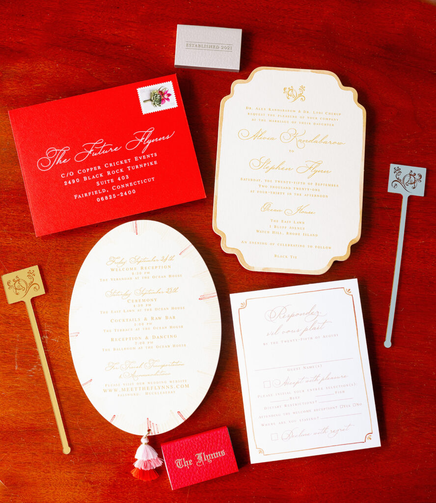 Wedding invitation suite flat lay with red and gold stationery. 