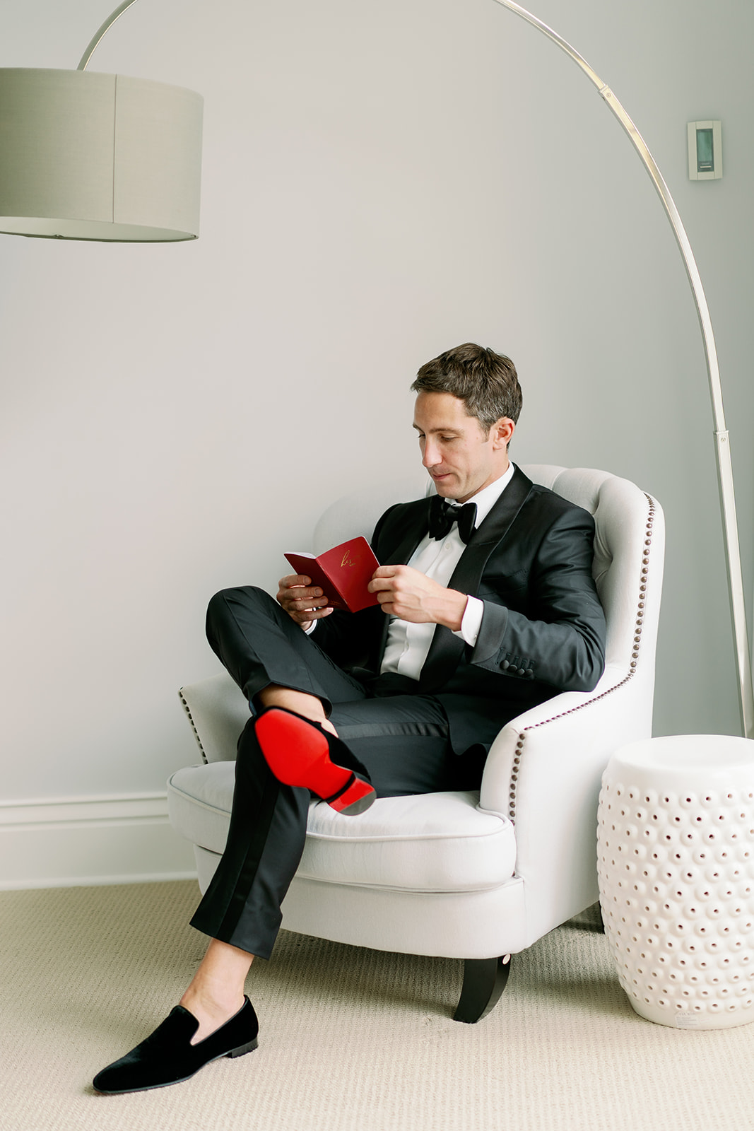 A stylish groom sitting down privately reading the heartfelt vows of his bride. 