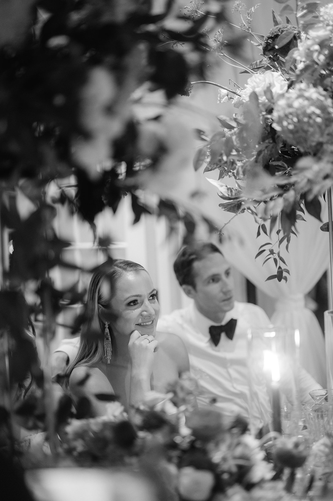 Romantic candid shot of a bride and groom listening to a heartfelt speech during their reception.