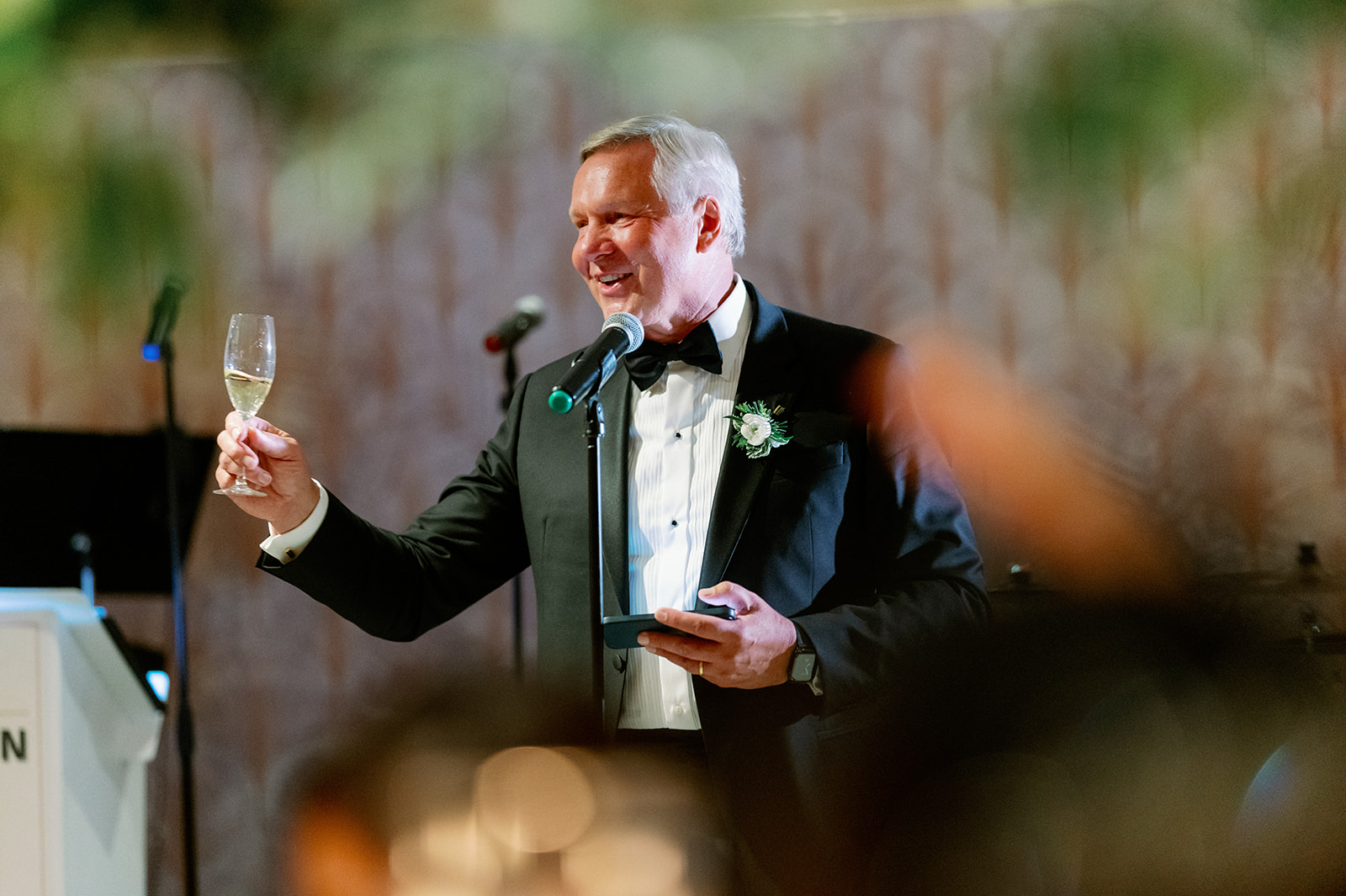 A man giving a speech and raising a glass to the bride and groom. 