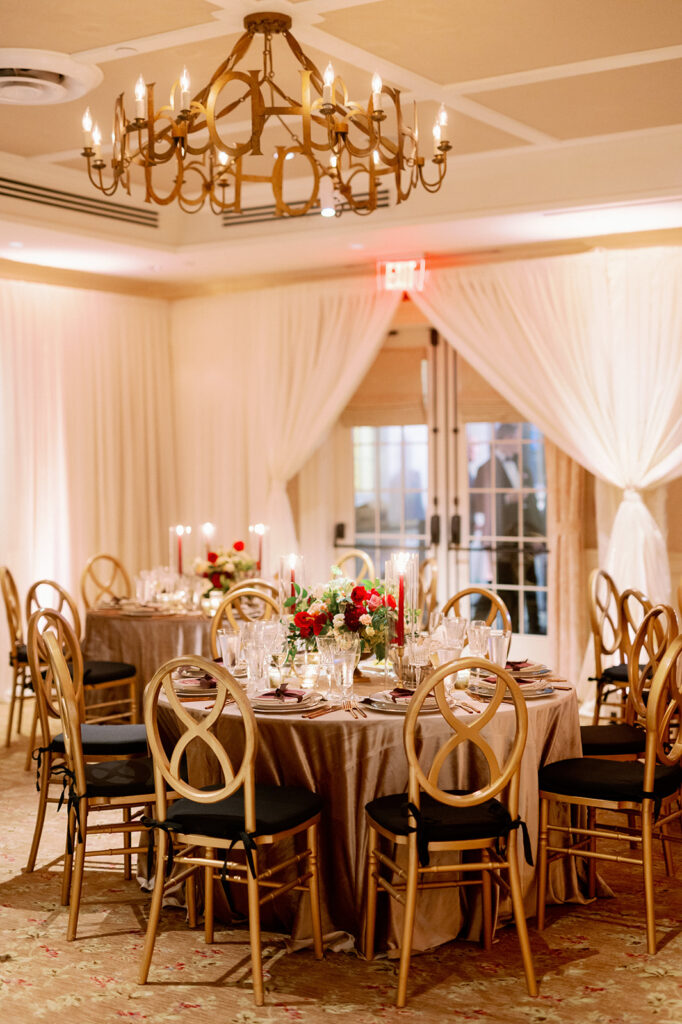 Luxury wedding reception at the Ocean House ballroom with round tables, black and gold chairs and floral centerpieces. 