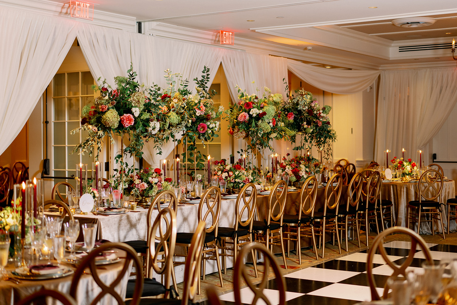 Luxury red and gold wedding reception in the ballroom of Ocean House in Rhode Island with hanging floral installations over the head table. 
