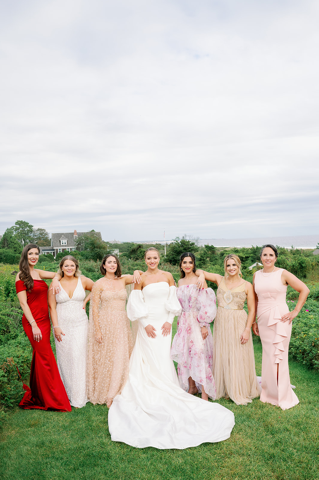 Romantic garden wedding bridal party with mismatched bridesmaid dresses in shades of pink, gold and red. 