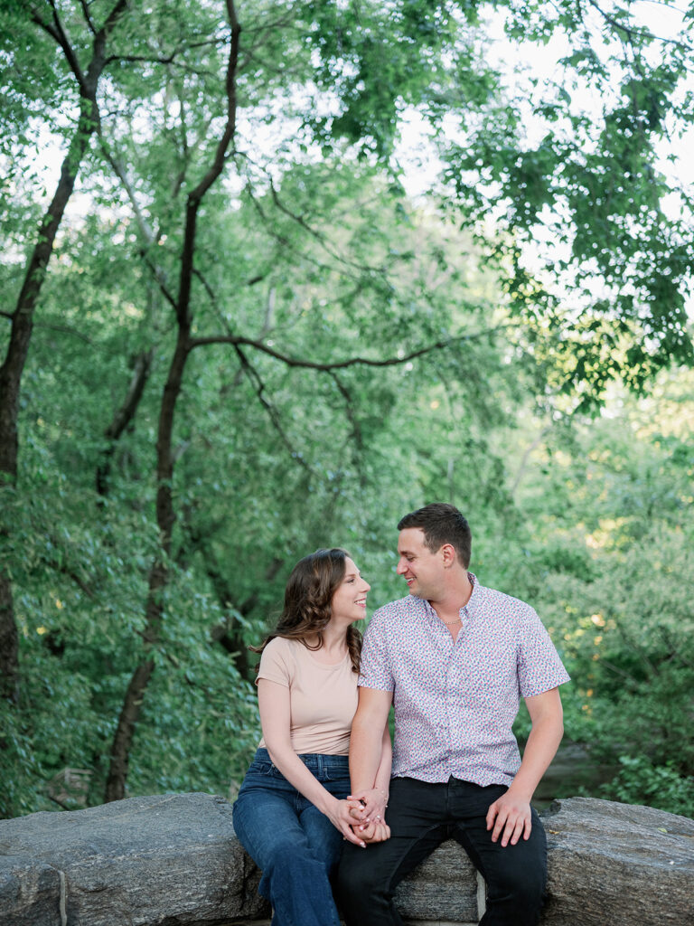 Couple sitting on a stone bench posing for their engagement photoshoot in Prospect Park in NYC. 