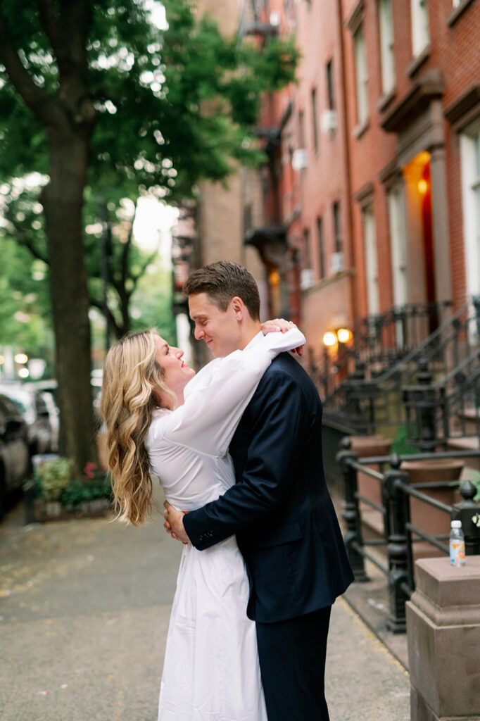 Couple embracing in front of West Village apartments for their romantic engagement photoshoot in New York City. 