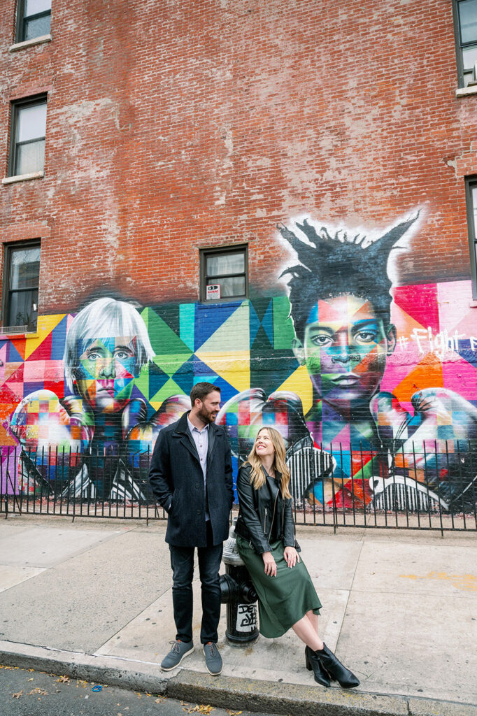 Couple sitting on a fire hydrant against a graffiti backdrop in Williamsburg, NY. 