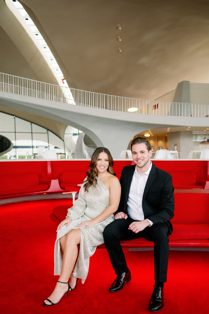 Couple sitting in a vintage, red Sunken Lounge at TWA Hotel.