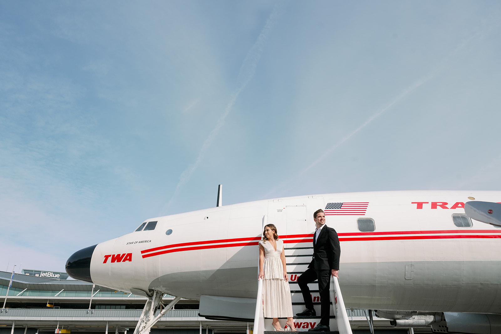 Couple posing on the stairs of the vintage Connie Aircraft at TWA Hotel in New York.