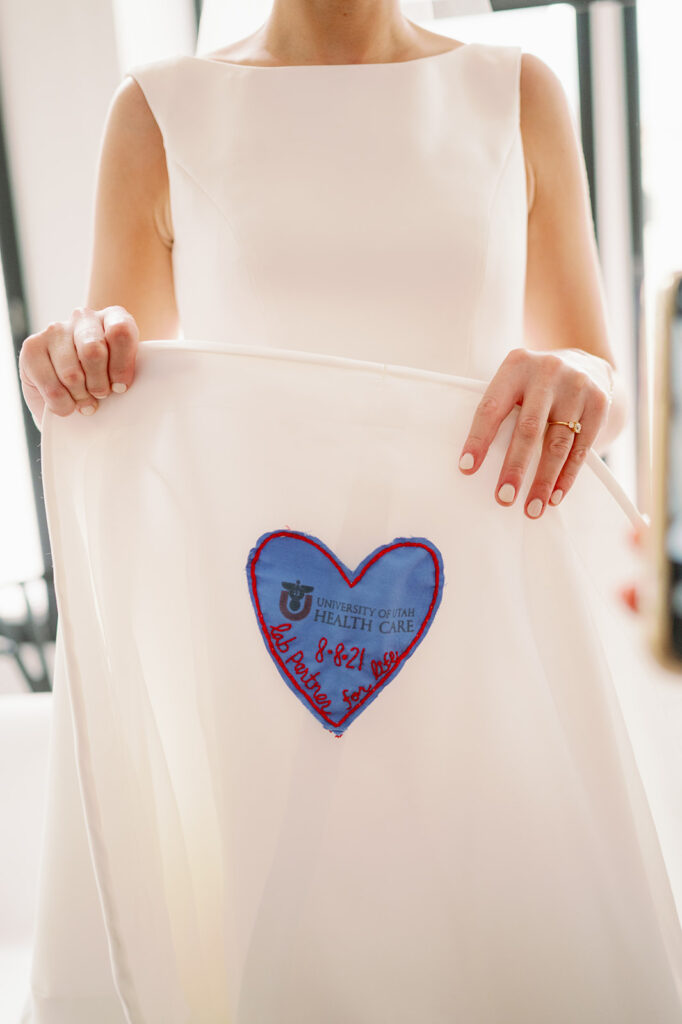 Bride holding up her "something blue" with a heart-shaped patch of her hospital scrubs.