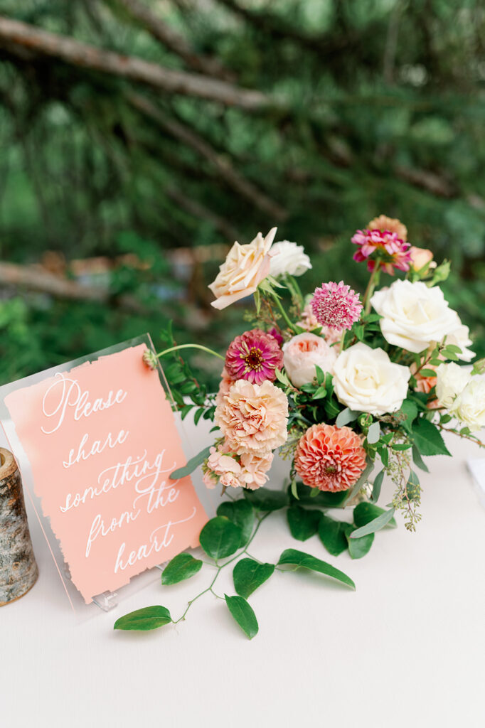 Summer wedding wedding welcome table with a pastel pink and cream floral bouquet.