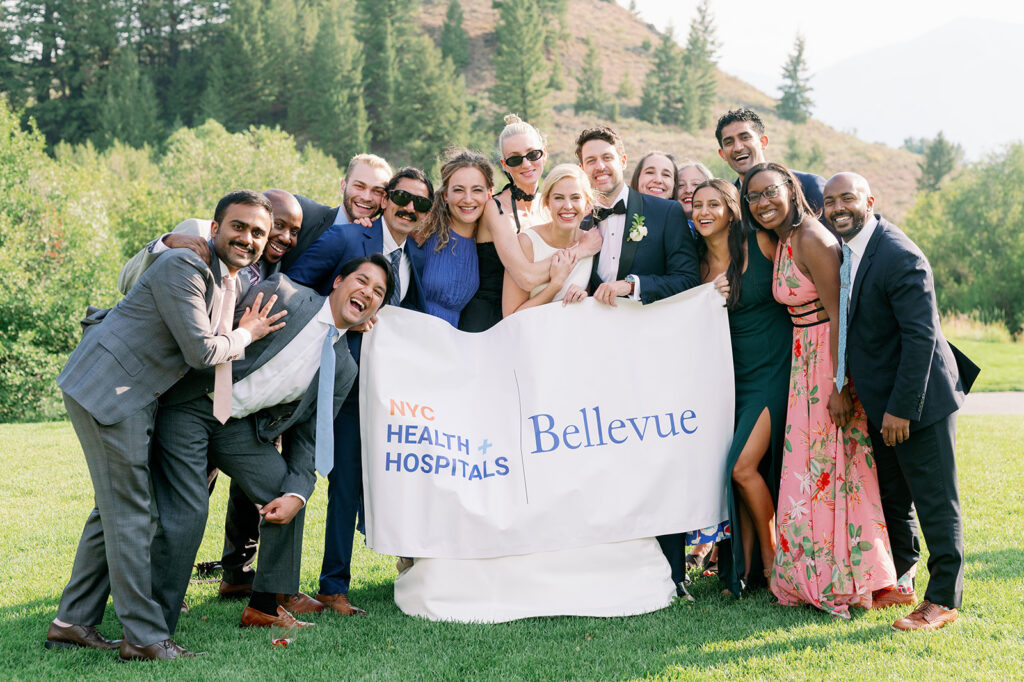 Bride and groom holding a NYC Health Hospitals banner with their colleagues.