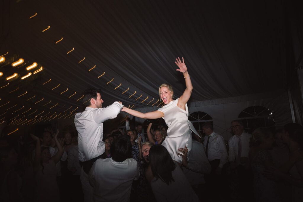 Bride and groom being lifted up during dance party.