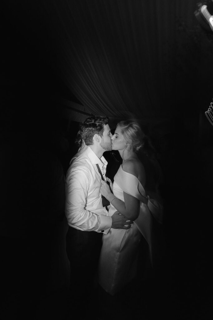 Bride and groom kissing during wedding dance party.