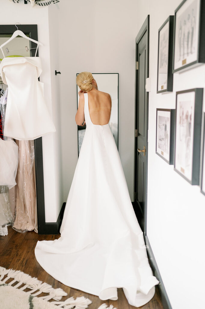 Bride standing in front of a mirror putting on earrings.