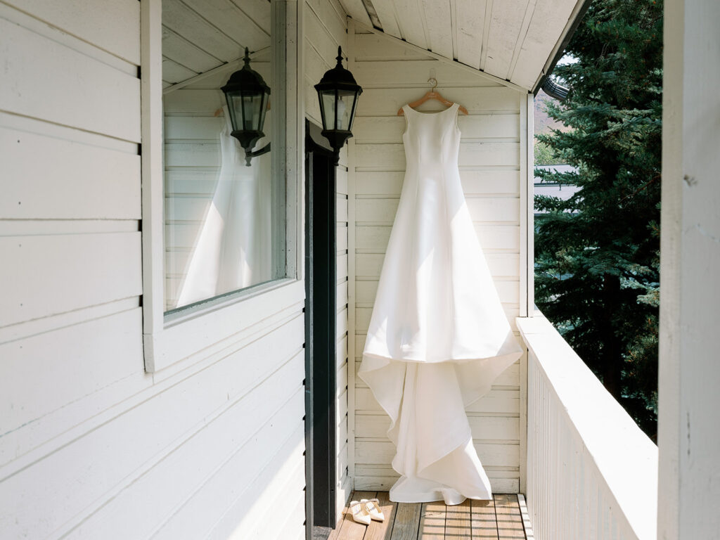 Sareh Nouri’s Dakota wedding dress hanging on a balcony in Sun Valley, Idaho.