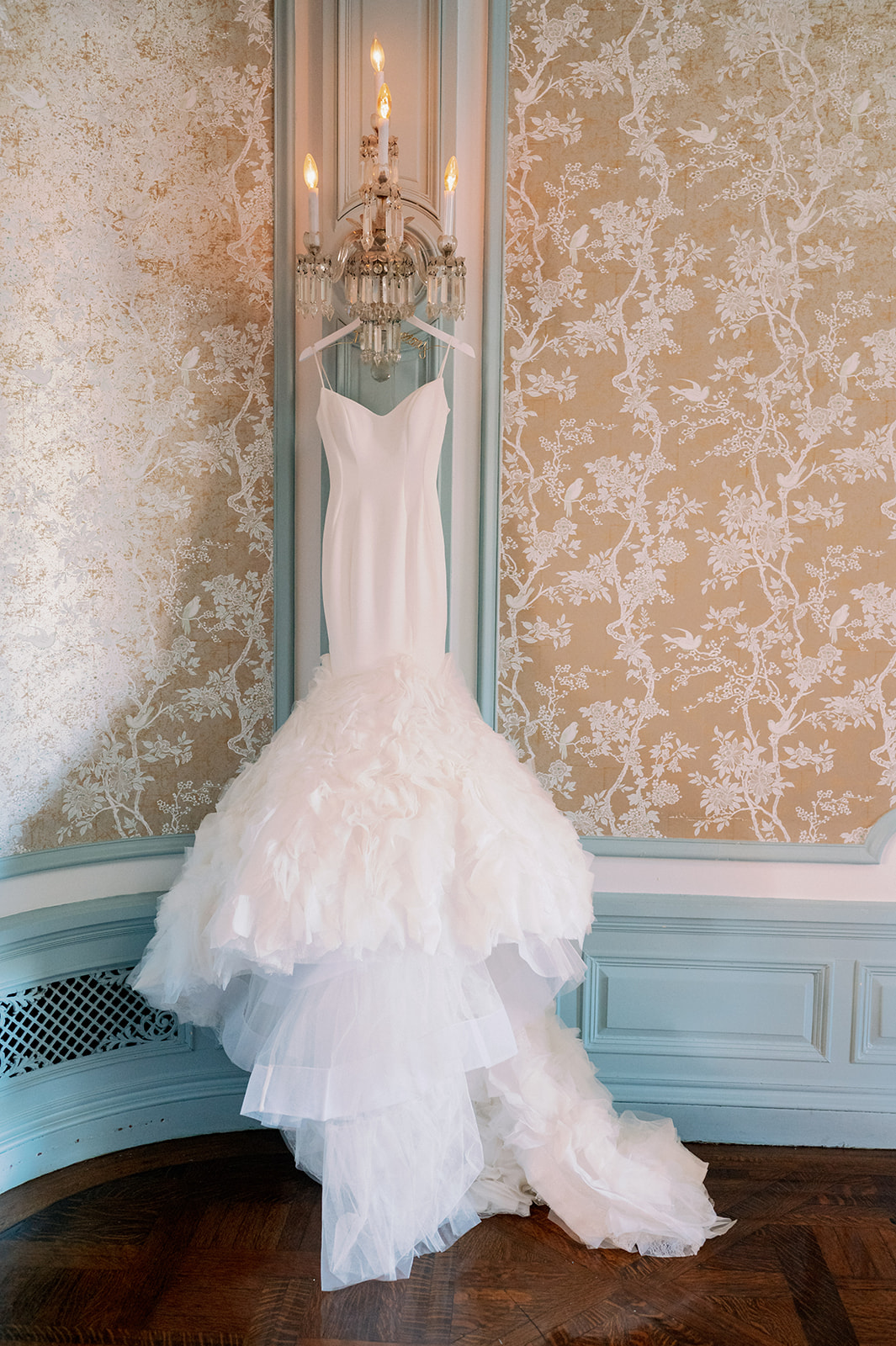 Mermaid wedding dress hanging on a wall sconce at the Bourne Mansion.