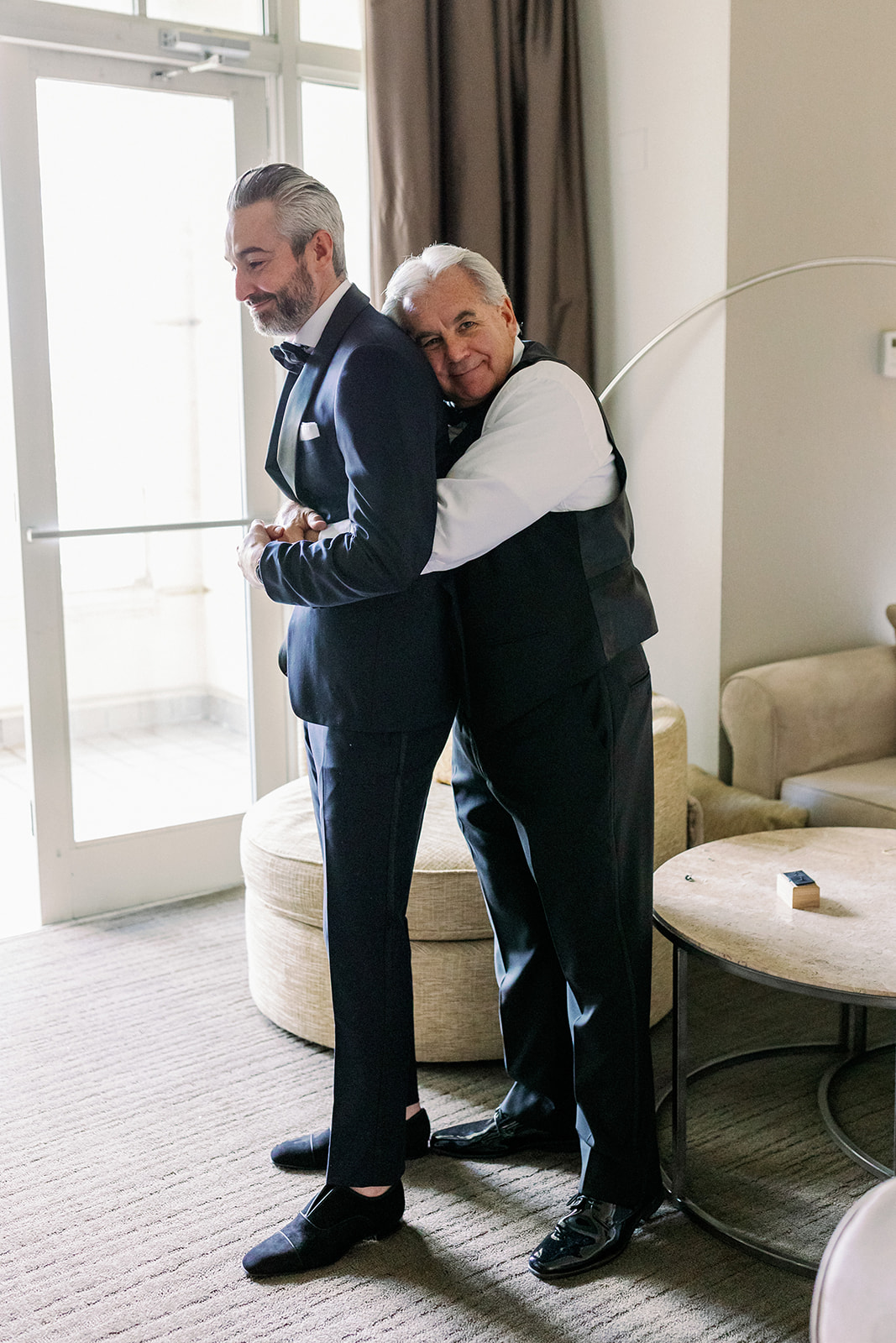 Groom's dad hugging him from behind while getting ready.