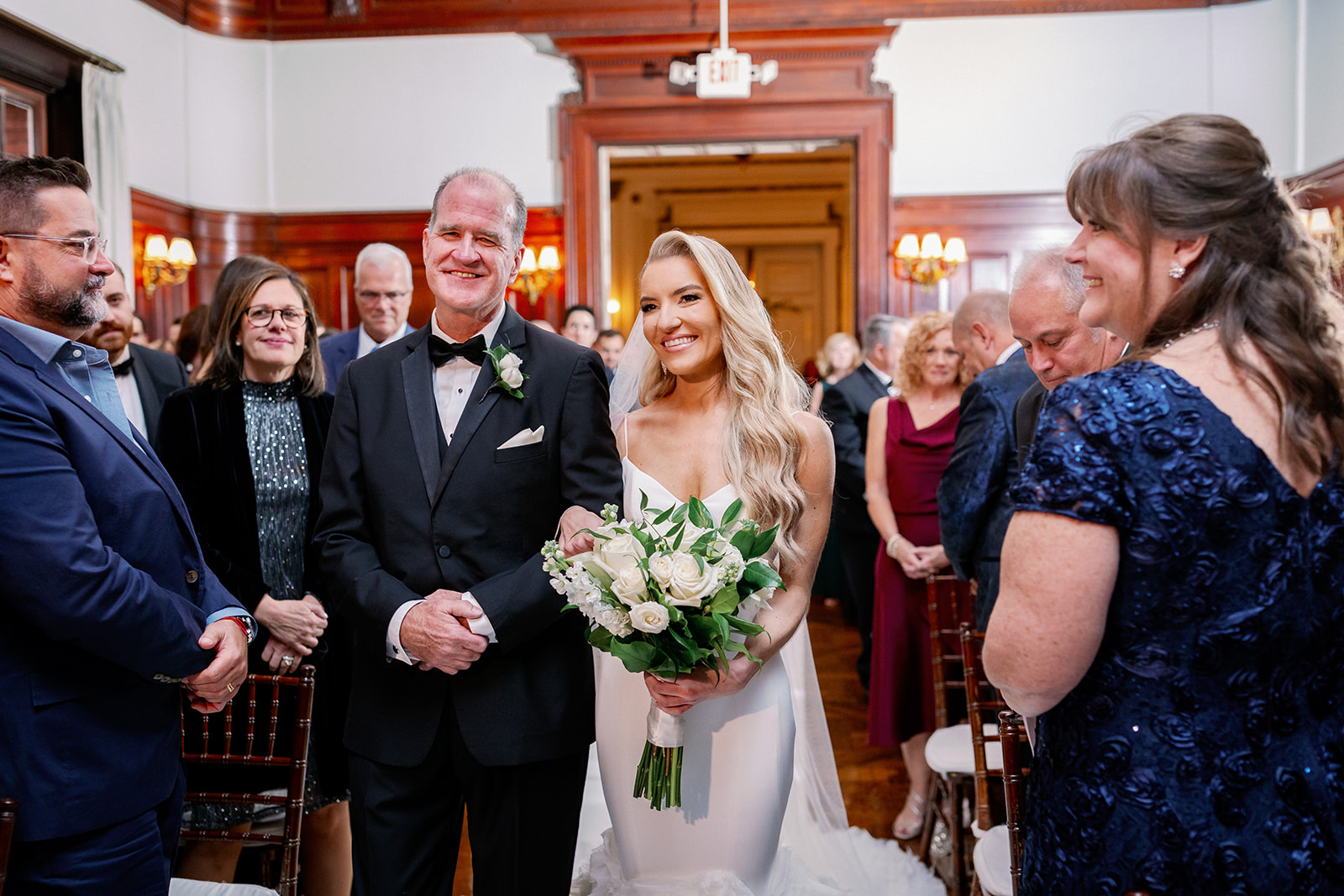 Bride walking down the aisle at her Bourne Mansion indoor wedding ceremony.