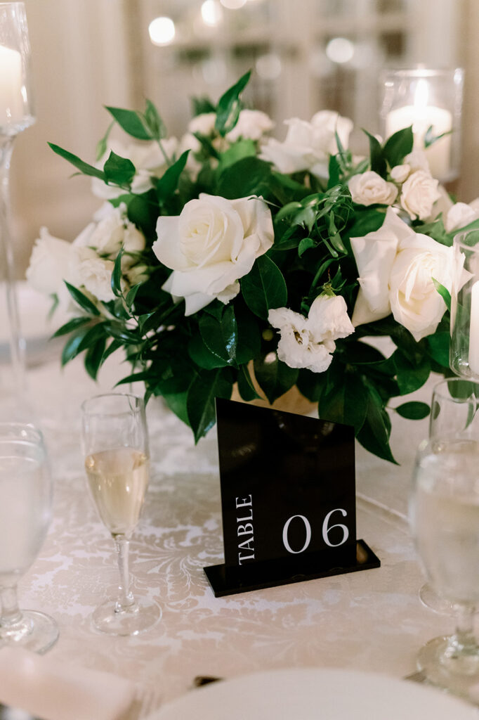 Luxury wedding reception table decor  with white roses and black table numbers.